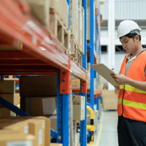 Warehouse worker in safety vest and helmet conducting inventory in supply chain management
